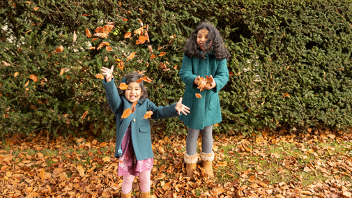Children enjoying autumn throwing leaves